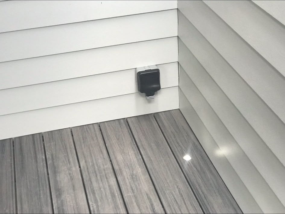 Weatherproof outdoor socket installed on external cladding beside decking