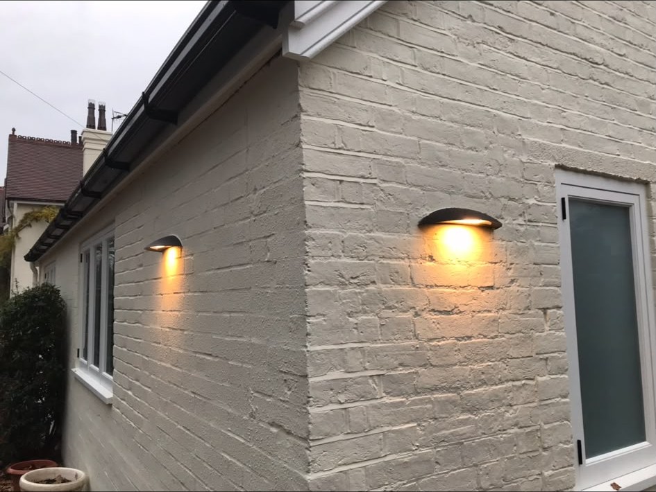 Weather-rated exterior wall lights installed on a rendered wall