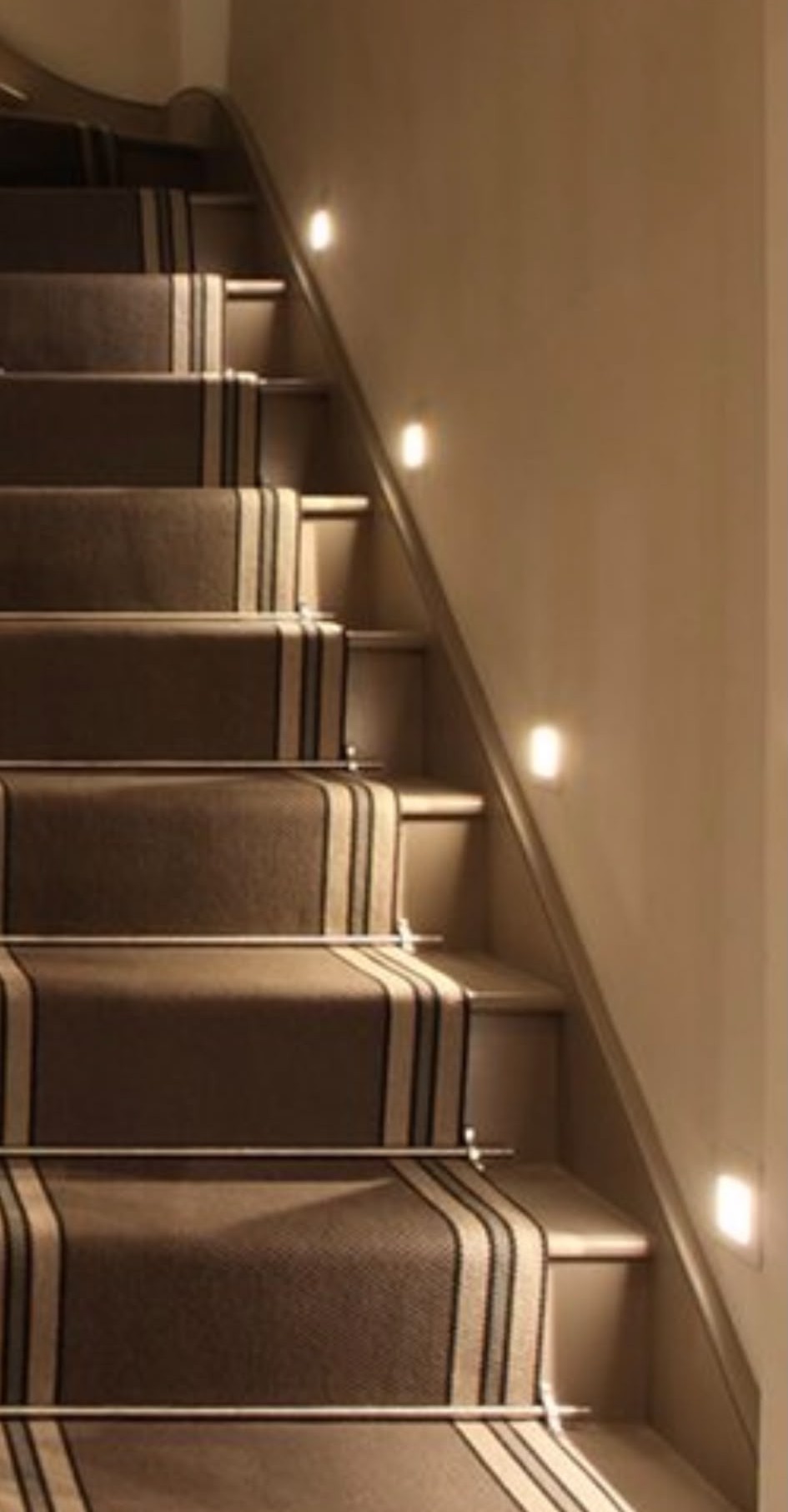 Recessed stair lights installed up a carpeted staircase