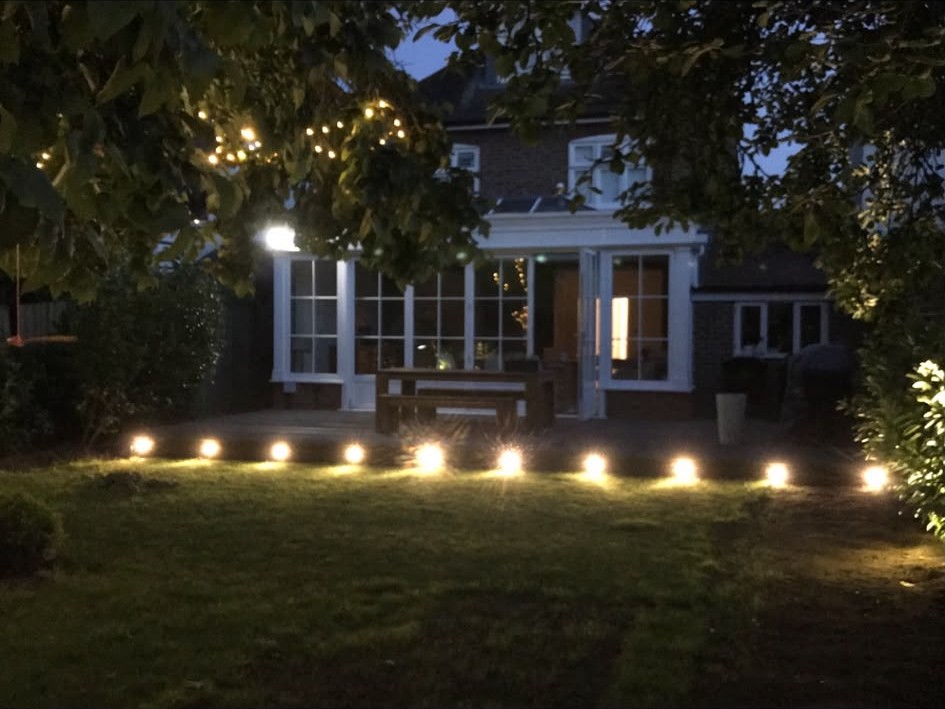 Garden lighting run along a lawn edge illuminating the rear of a house