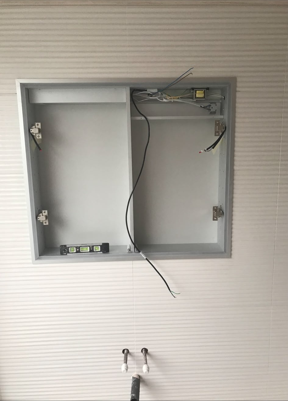 Illuminated bathroom mirror cabinet being wired into a recessed opening
