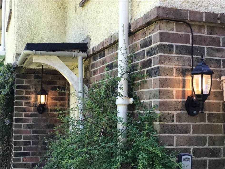 Exterior lantern wall lights installed on a brick porch